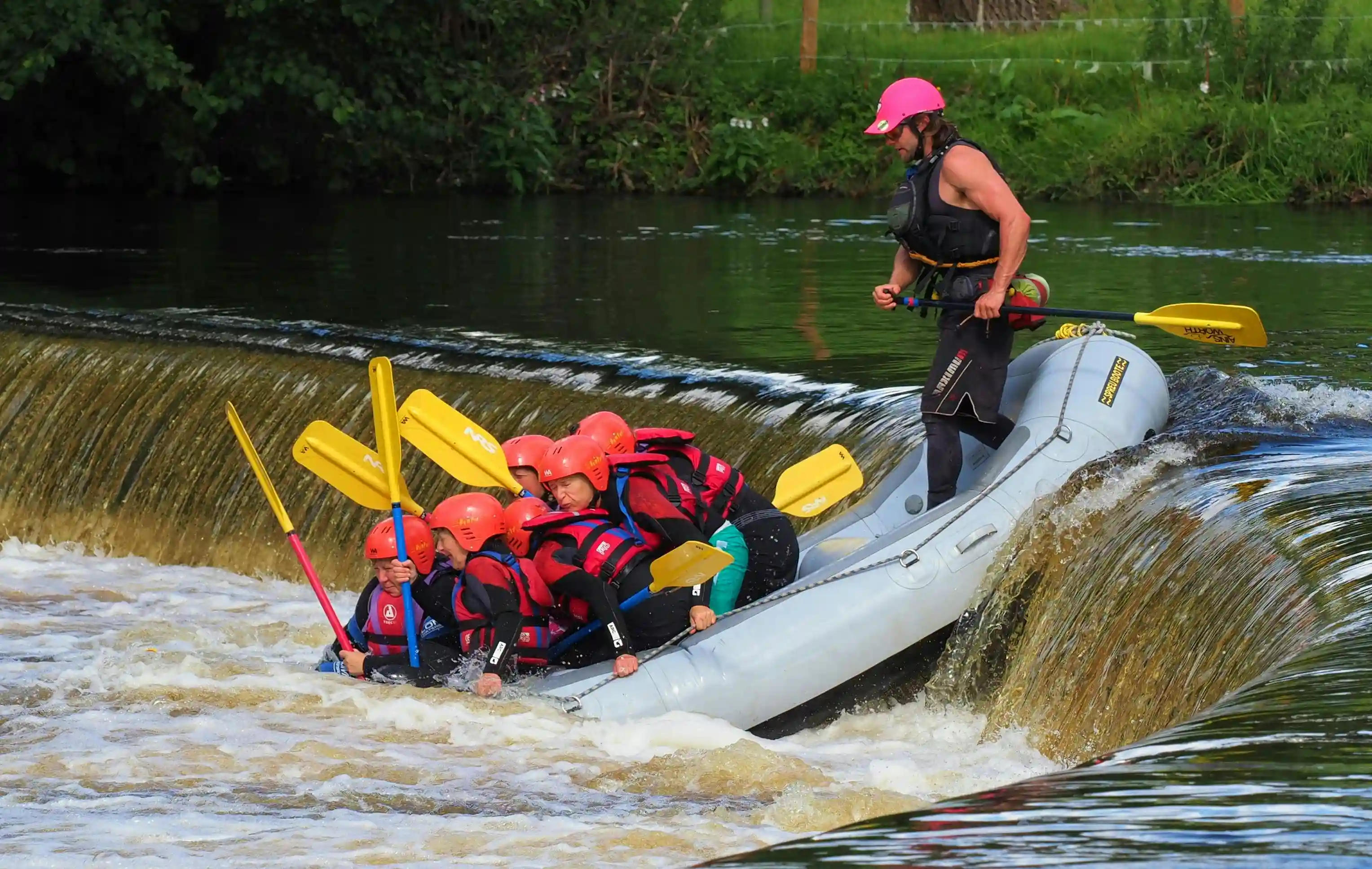 Group smiling and laughing while holding up their paddles in a raft